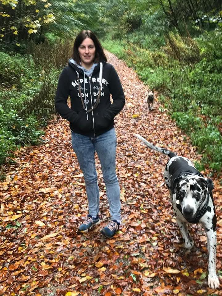 Nicola standing outdoors with one of her dogs.